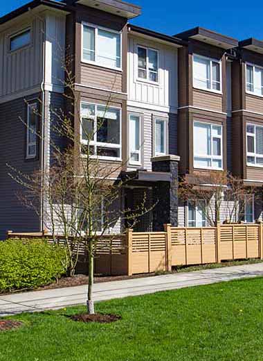 Modern low rise wood frame complex. Brand new apartment building on sunny day in spring with blooming trees.