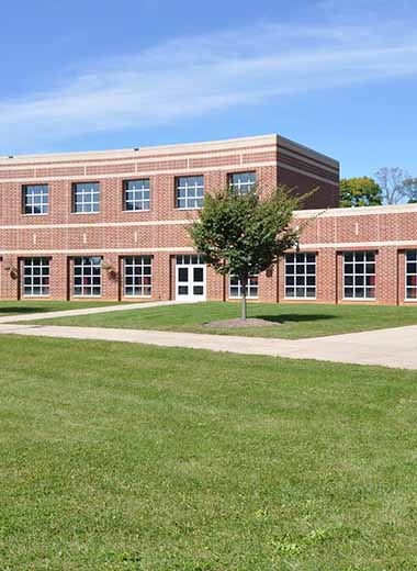 exterior of modern red brick school by a lush green lawn